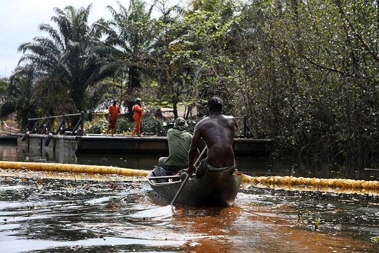 یکی از اعضای جامعه نمبه در حال پارو زدن پس از نشت نفت ، سانتا باربارا، نیجریه