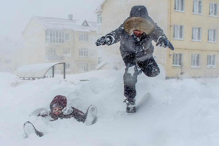 کودکان در هنگام طوفان برفی شدید در جزیره ساخالین بازی می کنند. یوژنو ساخالینسک، روسیه