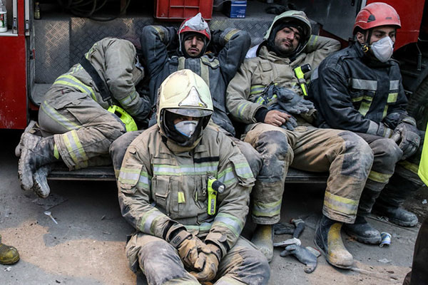 آتش نشانان غمگین و خسته در جستجوی بقایای همکارانشان
