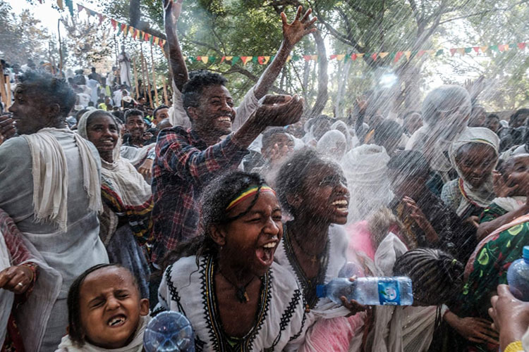 عبادت کنندگان ارتدوکس در حالی که در جشن تیمکات، مراسم تجلیل اتیوپی، با آب مقدس خیس می شوند، می خندند.<br />گوندار، اتیوپی