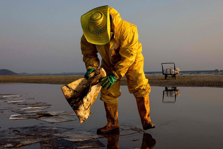 یک کارگر در حال تمیز کردن نفت خام در ساحل Mae Ram Phueng پس از نشت ناشی از نشت در یک خط لوله زیر دریا متعلق به شرکت سهامی عام پالایش نفت استار است.<br />رایونگ، تایلند