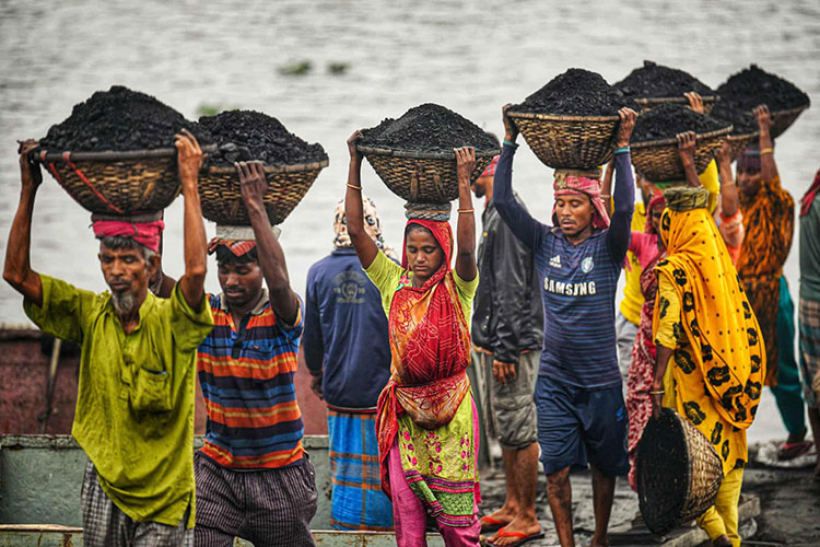 کارگران روزمزد بنگلادشی سبدهای زغال سنگ را از یک کشتی باری در گابتولی حمل می کنند. داکا، بنگلادش