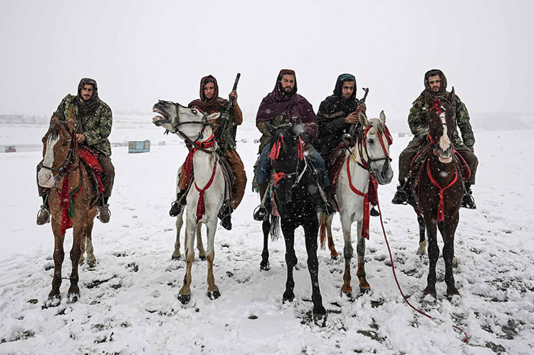 جنگجویان طالبان هنگام بارش برف در دریاچه قرغه سوار بر اسب گشت می زنند.کابل، افغانستان