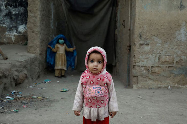 دختر یک ساله در ورودی خانه خانواده اش در یک زاغه ایستاده است.<br />کراچی. پاکستان