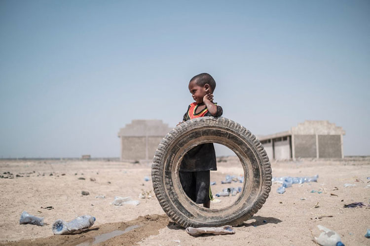 یک کودک آواره اتیوپیایی در کنار یک تایر فرسوده ایستاده است.<br />afdera، اتیوپی