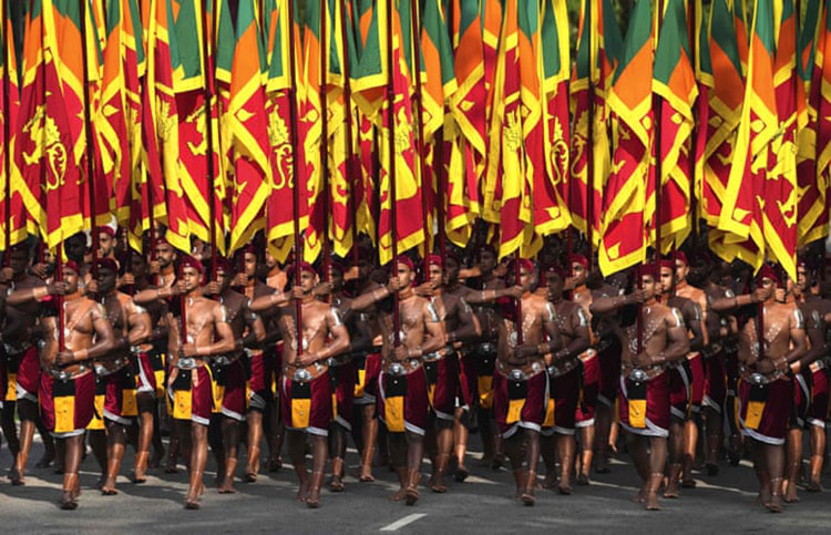 سربازانی که لباس های سنتی بر تن دارند پرچم های ملی را در جشن سالانه روز استقلال حمل می کنند.<br />کلمبو، سریلانکا