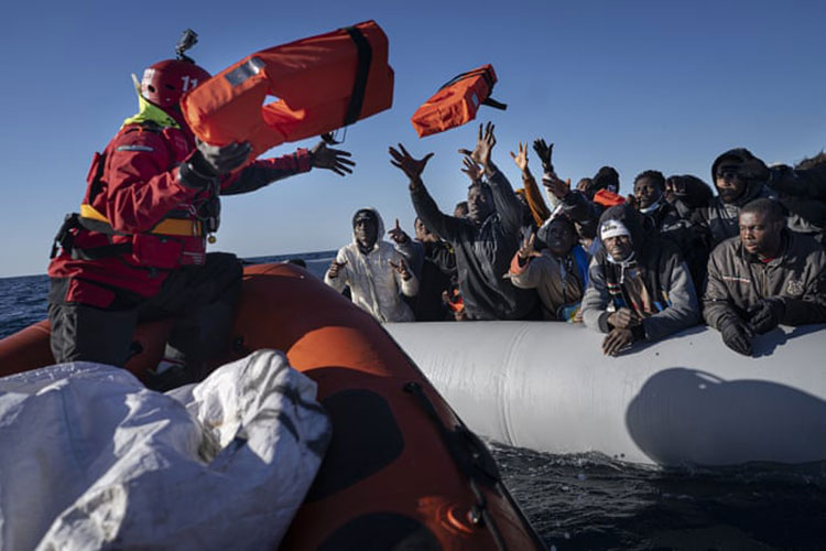 مهاجران از آفریقا، در یک قایق لاستیکی از نیرو های امدادی سازمان های اسپانیایی کمک و غذا دریافت می کنند.<br />سواحل لیبی، مدیترانه