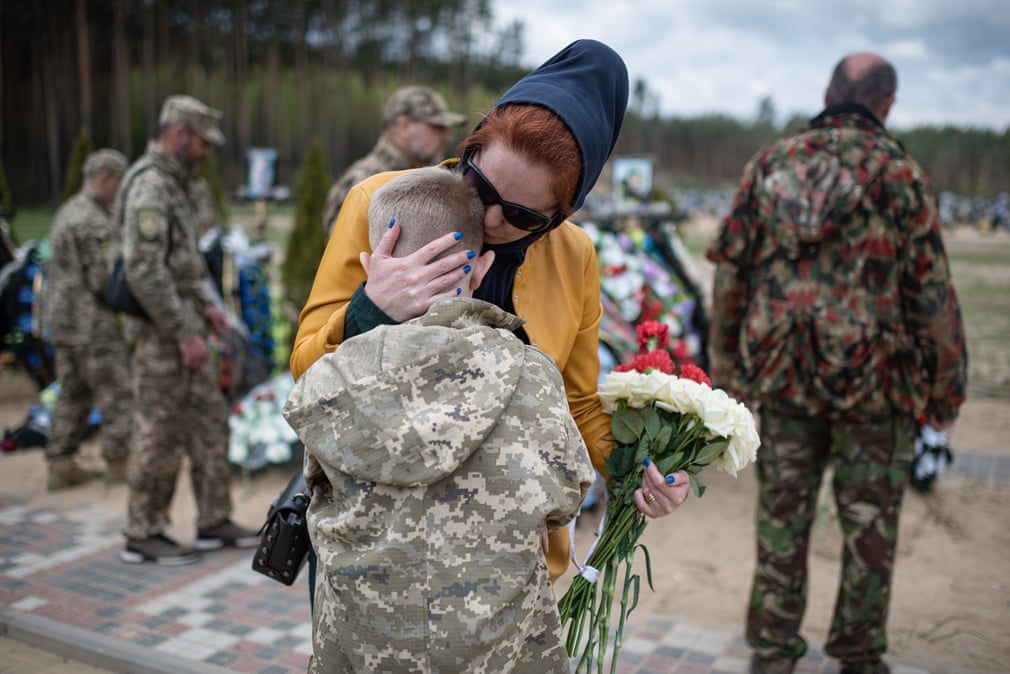 Alla (نوازنده اکراینی) درحال به آغوش کشیدن پسرش ساولی، در کنار قبر همسرش؛ همسر آلا در حمله روسیه به اوکراین کشته شد.