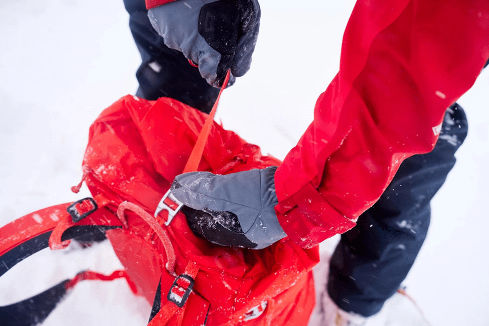  تصویر نیم نمای کوهنوردی که دستکش کوهنوردی پوشیده است و بند کوله کوهنوردی‌اش را محکم می‌کند 