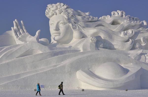 Visitors walk past a giant snow sculpture ahead of the 30th Harbin Ice and Snow Festival in Harbin