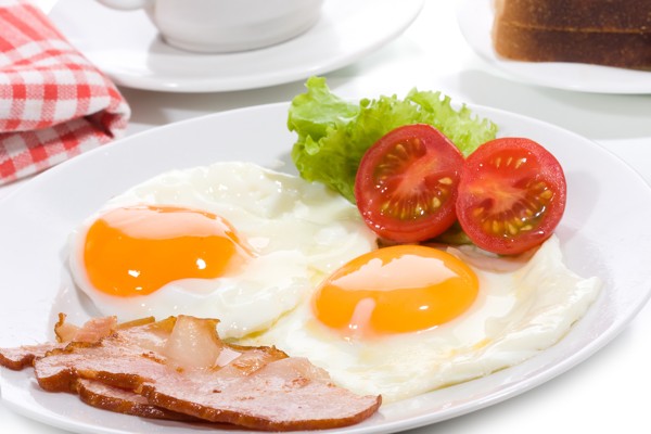 Breakfast with fried egg and bacon with vegetables