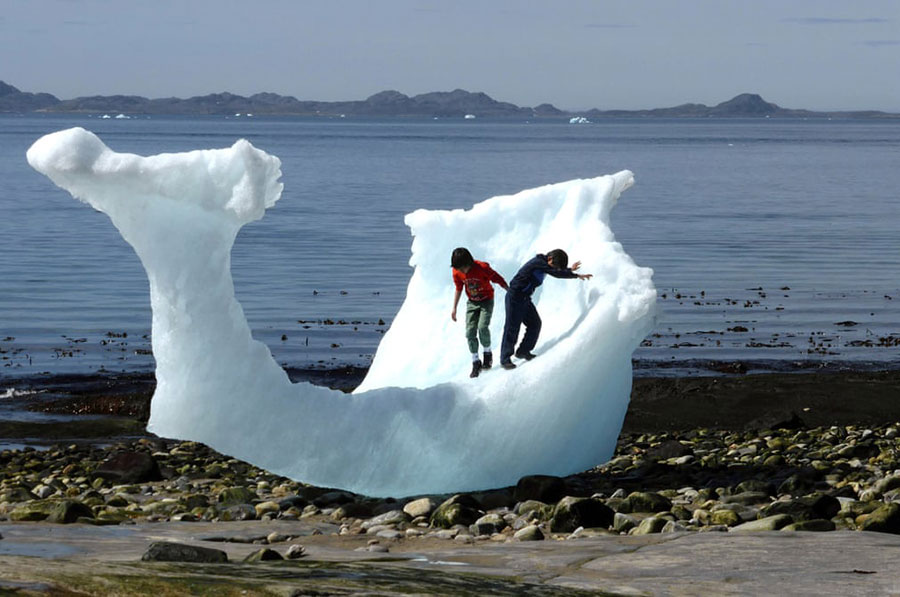 بازی کودکان گرینلندی با تکه یخ در حال آب شدن در ساحل این جزیره