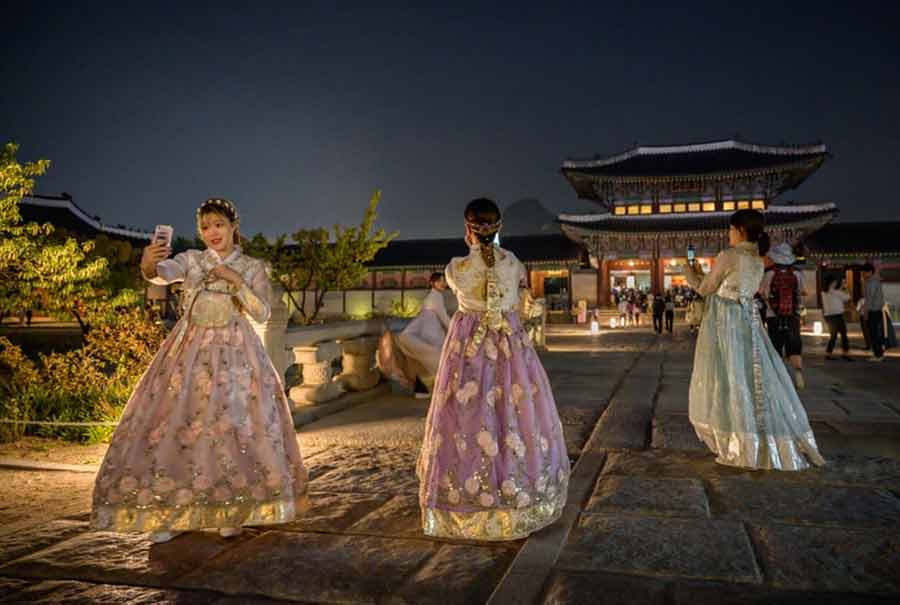 گردشگران کره‌ای با لباس سنتی در حال سلفی گرفتن در قصری تاریخی در شهر سئول