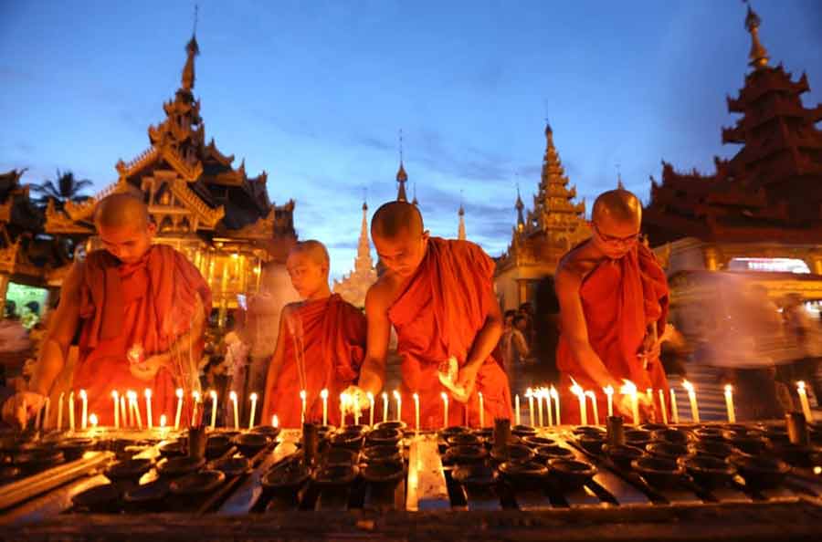 راهبان بودایی در معبدی در شهر یانگون میانمار در حال روشن کردن شمع در جشنواره‌ای آیینی
