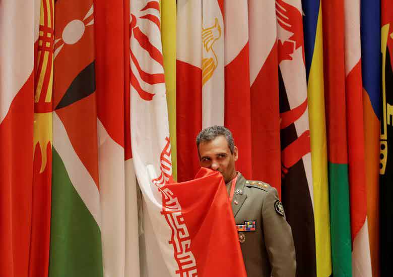 یک نظامی ایرانی در حال بوسیدن پرچم ایران در حاشیه حضور در اجلاس امنیتی شیانگ شان چین