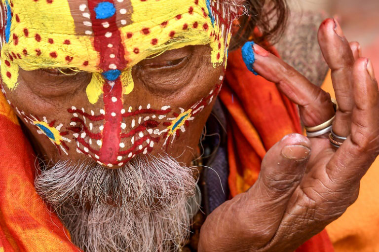 مرد مقدس هندو در حال رنگ آمیزی صورت در معبدی در کاتماندو نپال در جشنواره آیینی ماها شیواراتری