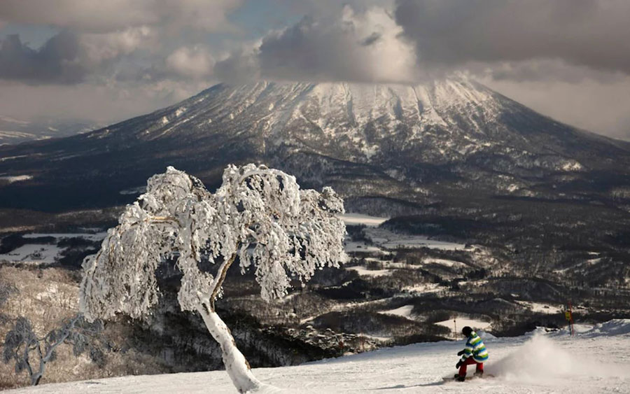 یک مرد اسنوبورد باز در منظره کوه یوتی در ژاپن