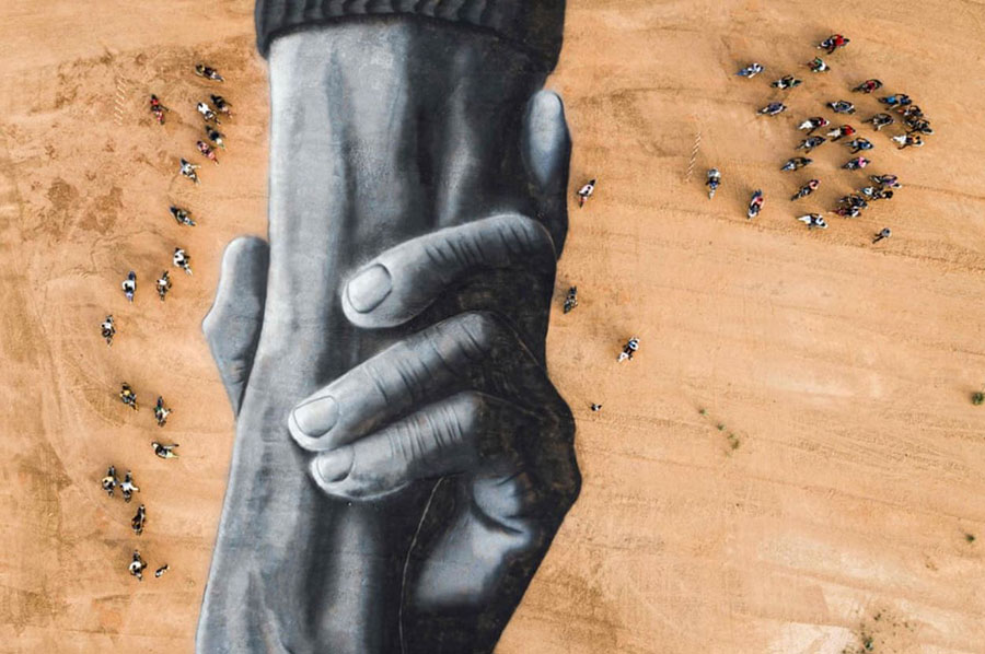 موتورسواران در اطراف یک نقاشی زمینی سه‌بعدی عظیم اثر یک هنرمند فرانسوی – سوییسی در بورکینافاسو