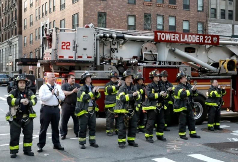 آتش‌نشانان نیویورکی در مقابل بیمارستانی در این شهر جمع شده‌اند و کادر درمانی را تشویق می‌کنند