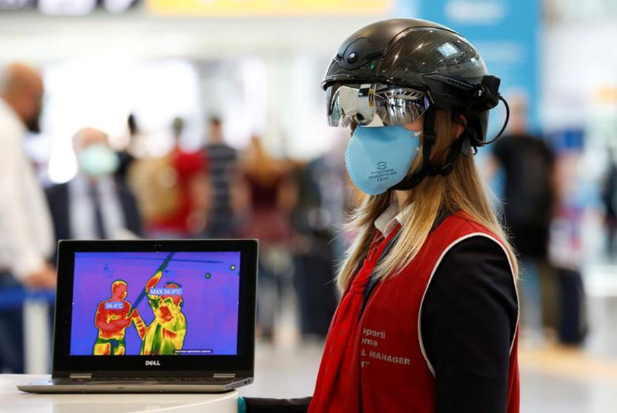 مامور فرودگاه بین‌المللی شهر روم ایتالیا با کلاه هوشمند مجهز به حسگر دمای بدن مسافران و دوربین حسگر دما در حال کنترل مسافران ورودی و خروجی
