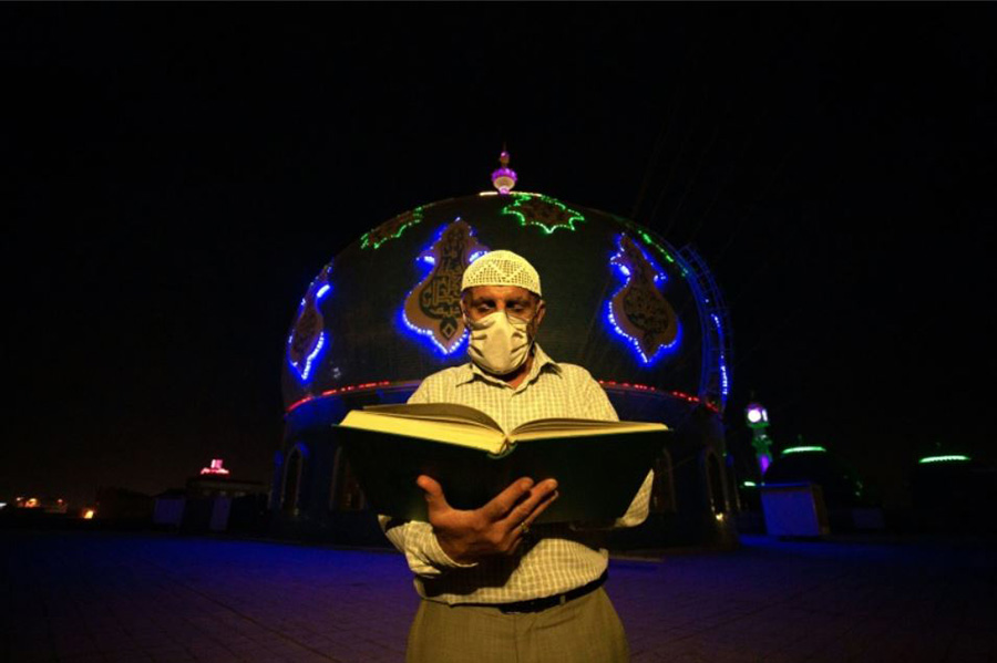 شهروند عراقی در حال قرائت قرآن در شب قدر در مقابل مسجد جامع موسوی در شهر بصره عراق