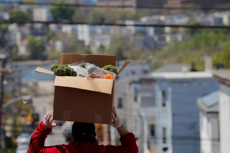 یک شهروند ساکن شهر چلسی در ایالت ماساچوست آمریکا در حال حمل مواد غذایی رایگان توزیع شده به خانه