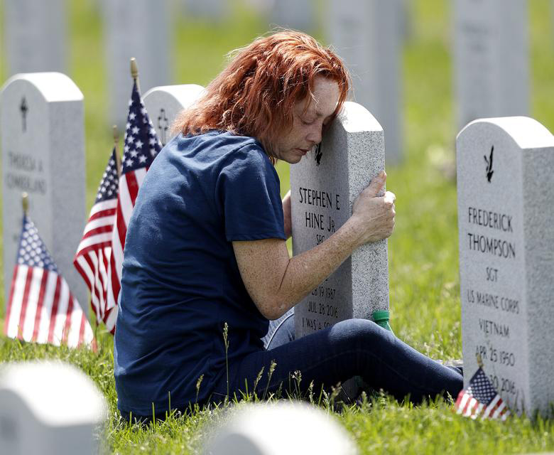 مادر آمریکایی در روز یادبود ( قربانیان جنگ) بر سر قبر فرزندش در گورستان شهر سویل در ایالت اوهایو نشسته است