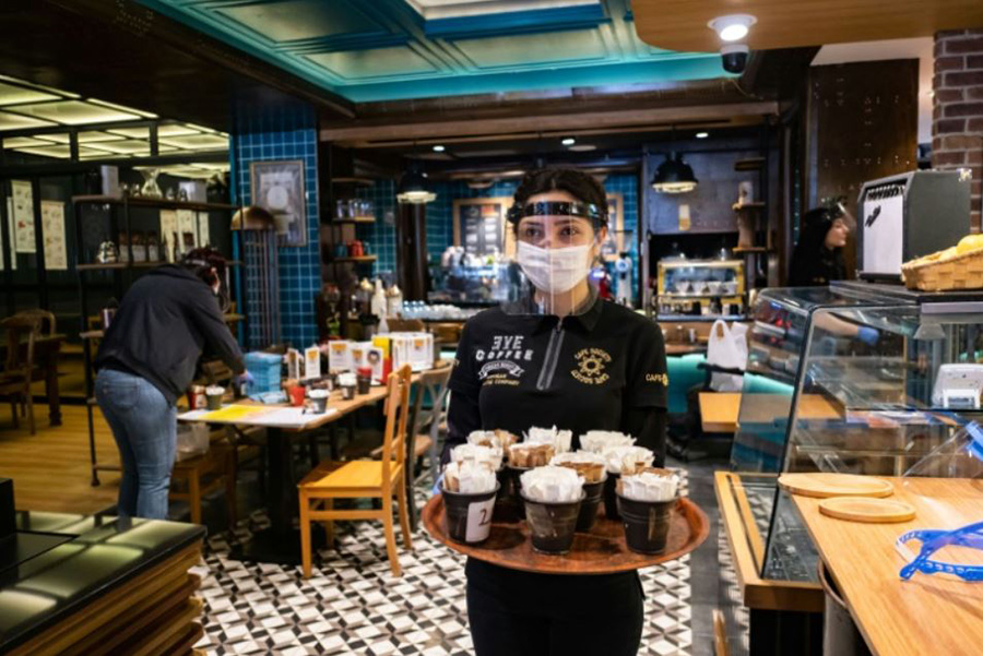 کارمند یک کافه در استانبول ترکیه با وسایل محافظ شخصی در حال پذیرایی از مشتریان