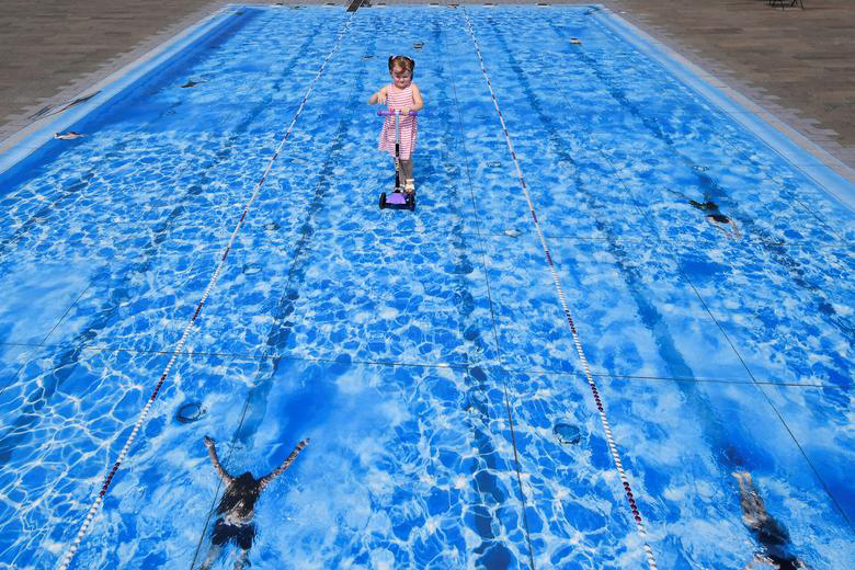 دختر خردسال اسکوترباز روی یک نقاشی سه‌بعدی از استخر در شهر لندن